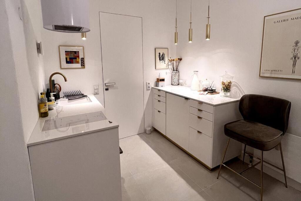 a white kitchen with a chair and a counter at Exclusive apartement in historic center in Linz
