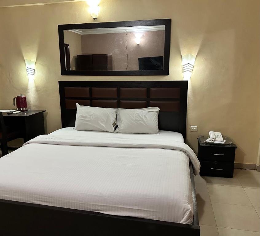 a bedroom with a large bed with a mirror on the wall at Whitehouse Msquare Hotel in Ikeja