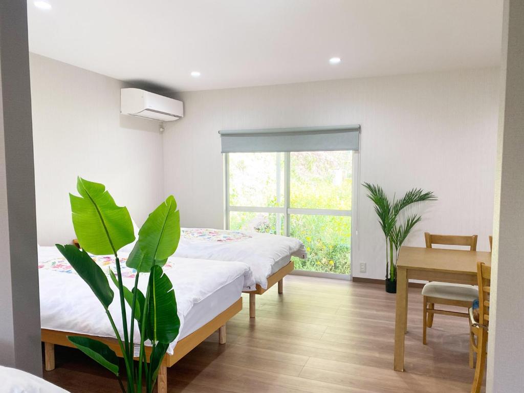 a bedroom with two beds and a table and a plant at ゆふの音 in Yufuin