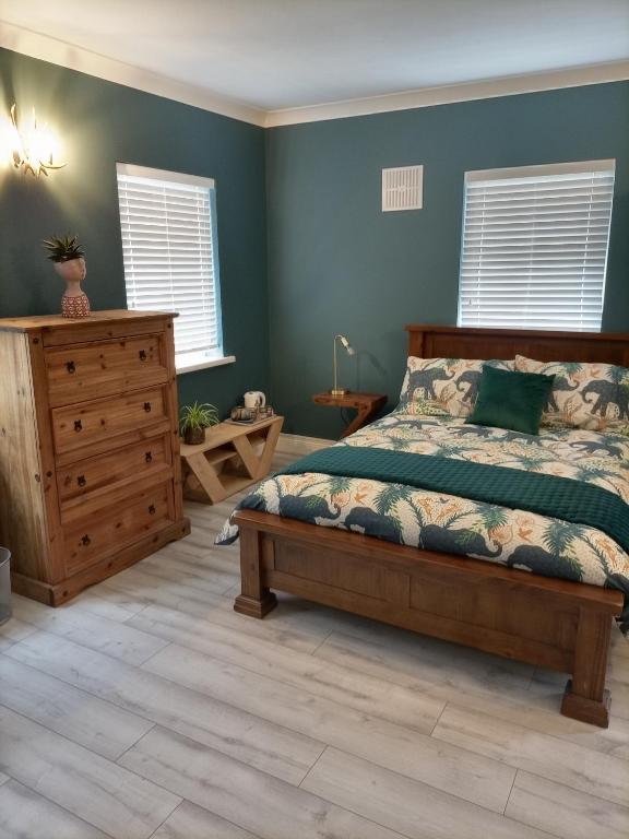 a bedroom with a bed and a dresser and windows at Applelea House in Rosslare