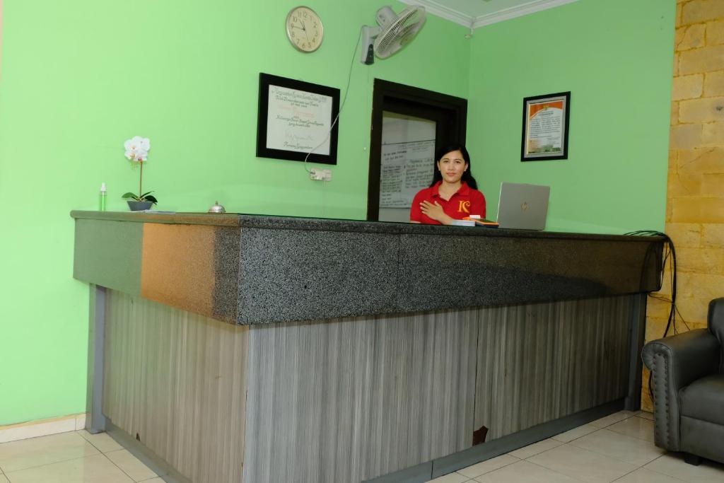 a woman standing behind a counter with a laptop at The Kirana Purnama Semarang in Semarang