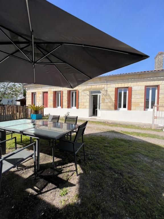 a table and chairs under a large black umbrella at Charmante maison au cœur du medoc in Cussac-Fort-Medoc