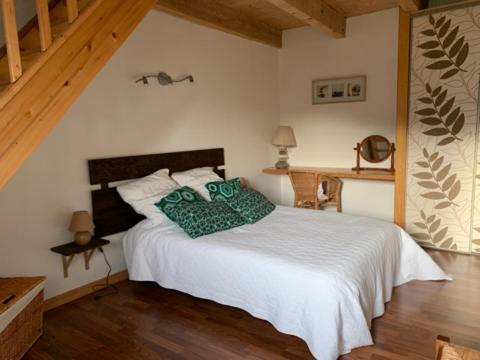 ein Schlafzimmer mit einem weißen Bett und grünen Kissen in der Unterkunft Logis du lac à Madic in Madic