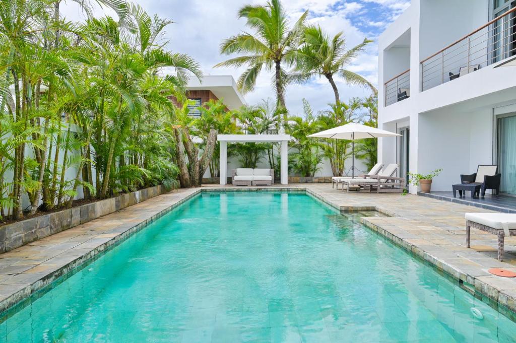 a swimming pool in the backyard of a house with palm trees at Villa Horizon by Dream Escapes, Beachfront Villa in Pointe aux Cannoniers