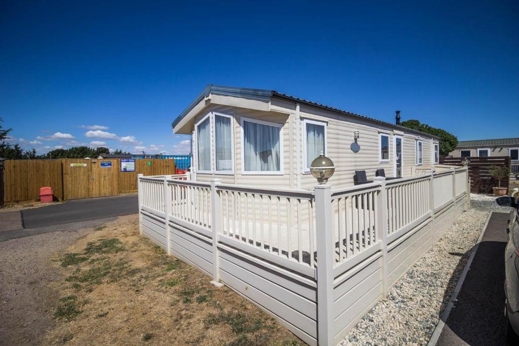 費利克斯托的住宿－6 Berth Caravan With Decking And Wifi At Suffolk Sands Holiday Park Ref 45082c，白色的小房子,有白色的围栏