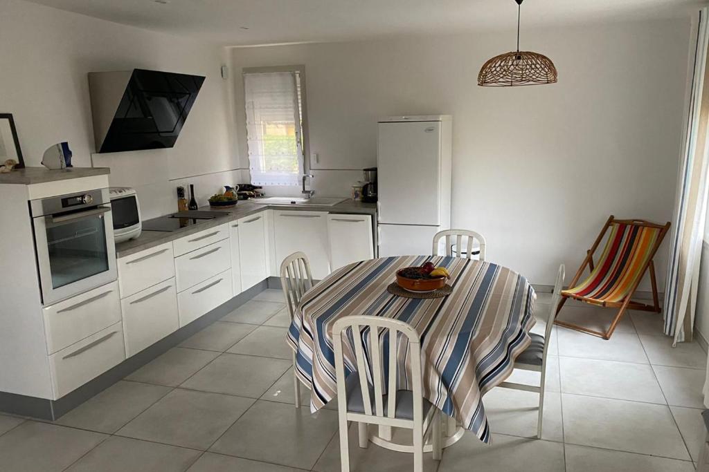 - une cuisine blanche avec une table et des chaises dans l&#39;établissement Spacious apartment in the heart of Narbonne Plage, à Narbonne