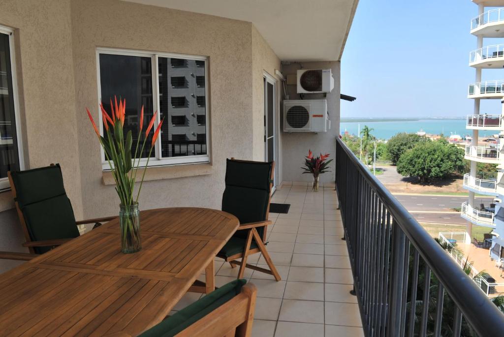 a balcony with a wooden table and chairs and a table at Inner city Cardona Court apartment in Darwin