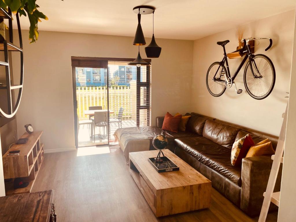 sala de estar con sofá y bicicleta en la pared en Mo's Explorer Cape Town Vacation Apartment, en Ciudad del Cabo