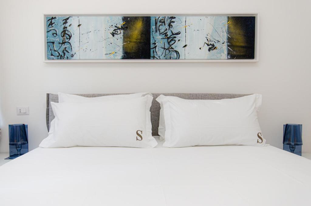 米蘭的住宿－Schiaparelli 4，一张带两个枕头的白色床和上面的绘画