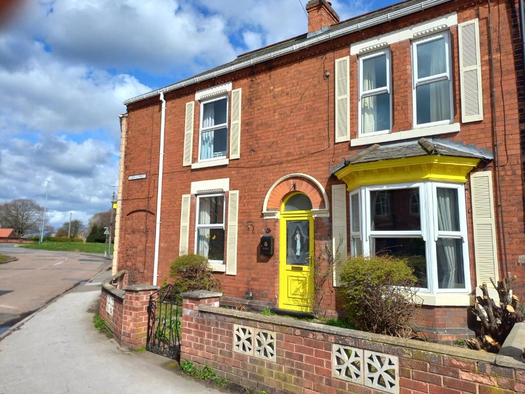 レットフォードにあるCharming 4-Bed Victorian House in Retfordの通り側の黄色い扉のあるレンガ造りの家