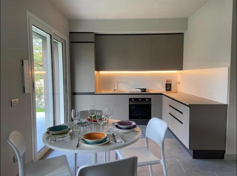 una cocina con mesa blanca, sillas y una mesa con gafas en Grazioso appartamento con giardino privato en Asti