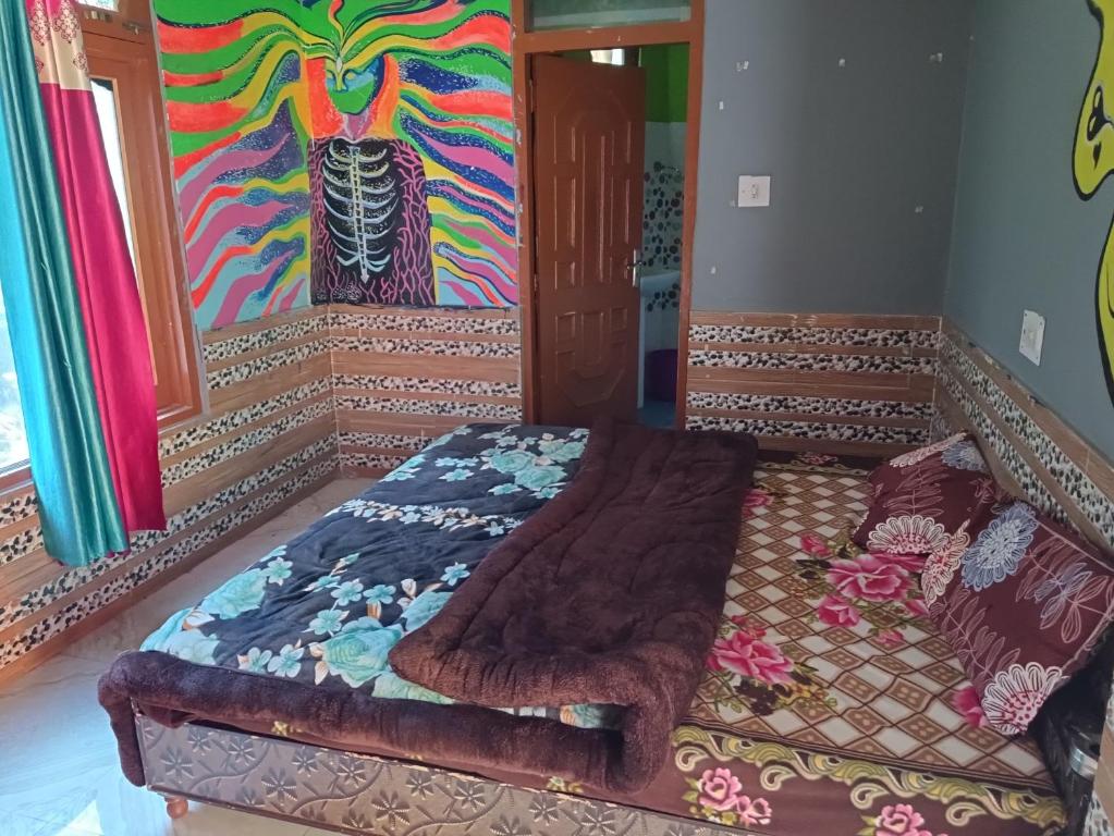 Ce lit se trouve dans un dortoir orné d'une peinture murale. dans l'établissement Dog n Hill, à Kasol