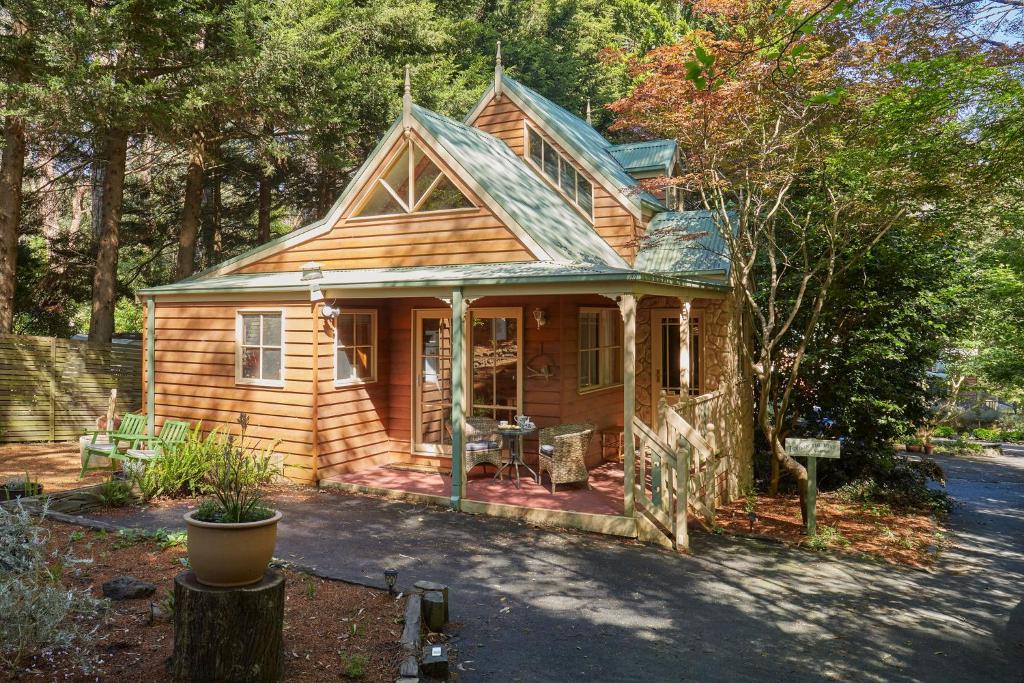 een klein houten huis met een veranda bij Fernhem Cottages- Love in the Mist in Emerald