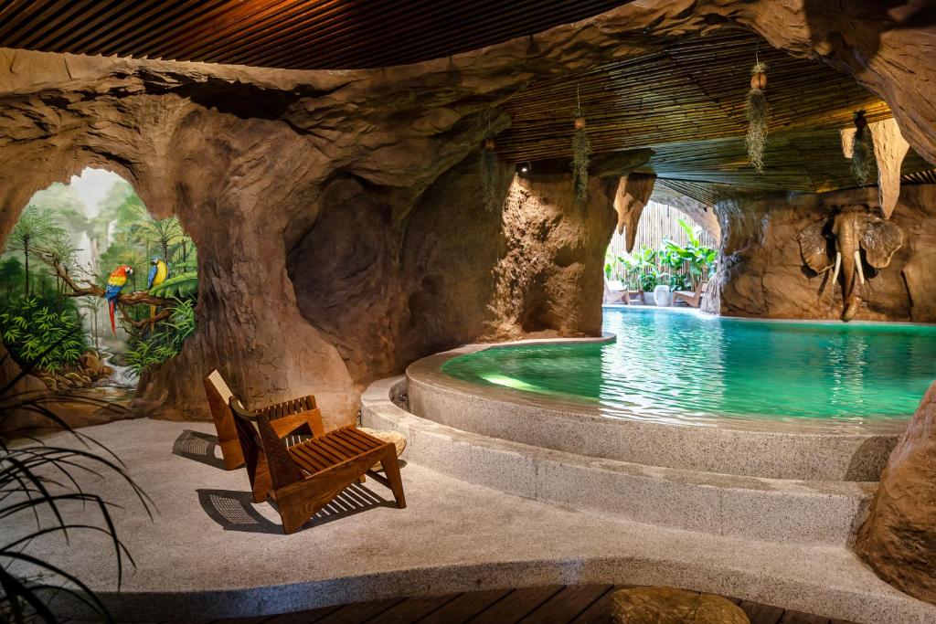 a pool in a cave with a bench and a chair at KunKin Garden Aparthotel in Ho Chi Minh City