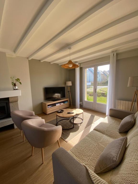 uma sala de estar com um sofá e cadeiras e uma televisão em maison de vacances ninette em Névez