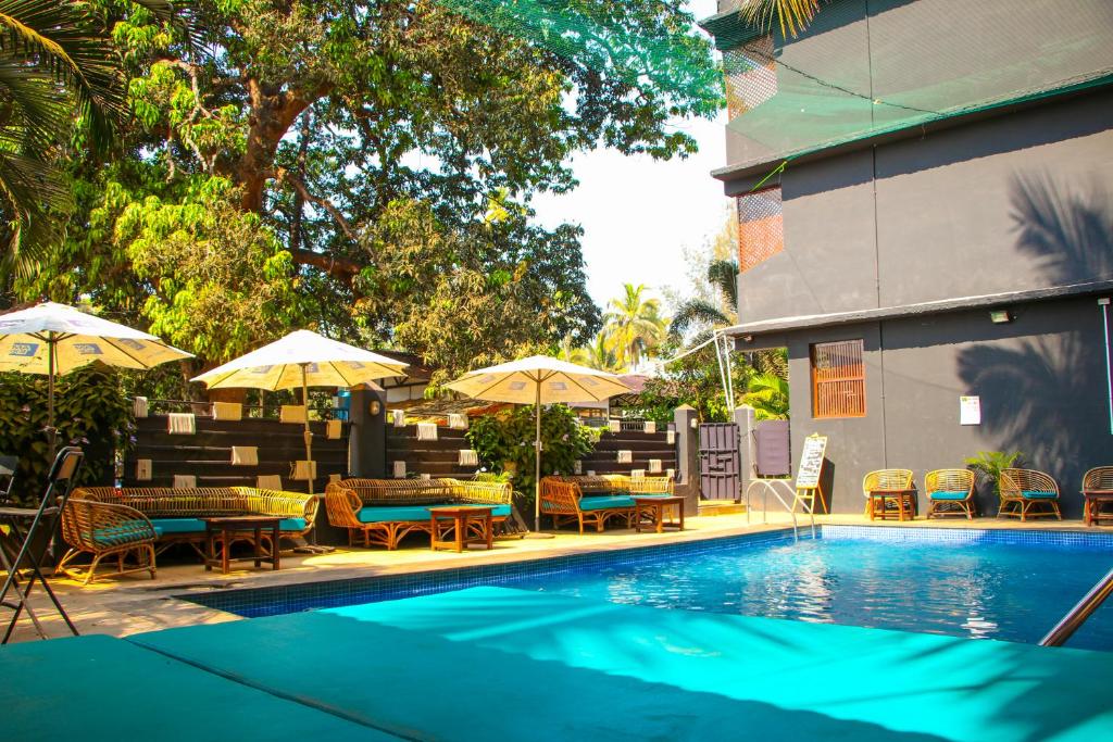 a swimming pool with tables and chairs and umbrellas at Pappi Chulo Morjim in Morjim