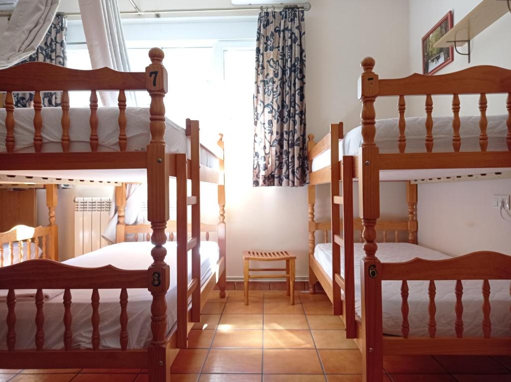 two bunk beds in a room with a window at Albergue de Peregrinos Ultreia et Suseia in Sigüeiro