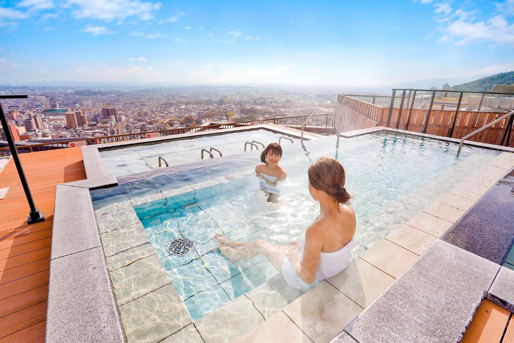 two women in a swimming pool on top of a building at Ooedo Onsen Monogatari Minoh Kanko Hotel in Minoo
