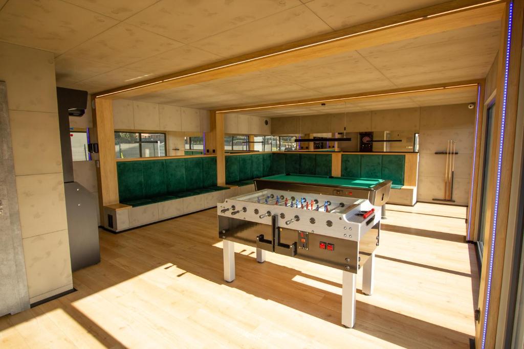 Bright game room with foosball table, green-upholstered bench seating and pool table.