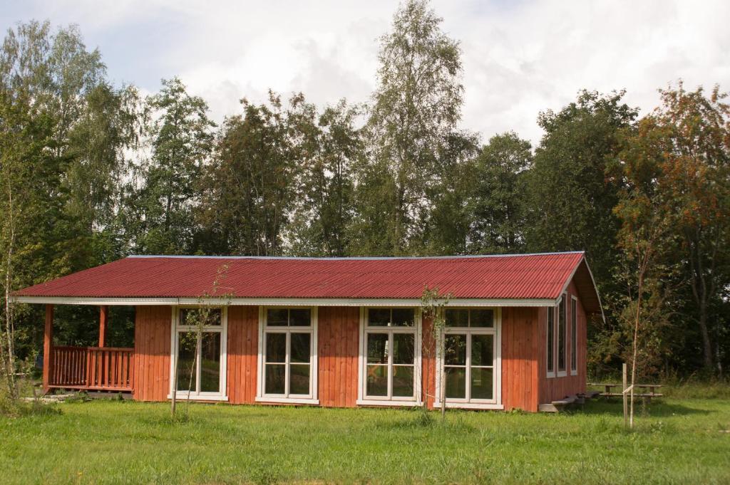 una casa roja con techo rojo en un campo en Atpūtas komplekss Kalves, en Mordanga