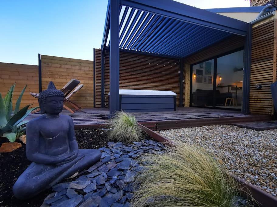 un giardino con una statua davanti a una casa di Gîte avec Spa a Saint-Marcan
