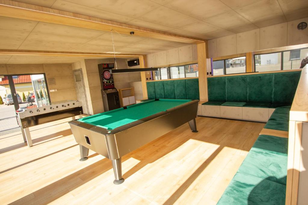 Angled view of pool table centered in wood-floored game room with green banquette seating.