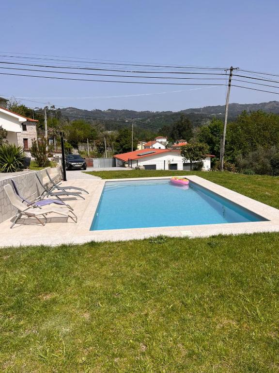 a swimming pool with two chairs in a yard at Casa dos Doces in Póvoa de Lanhoso