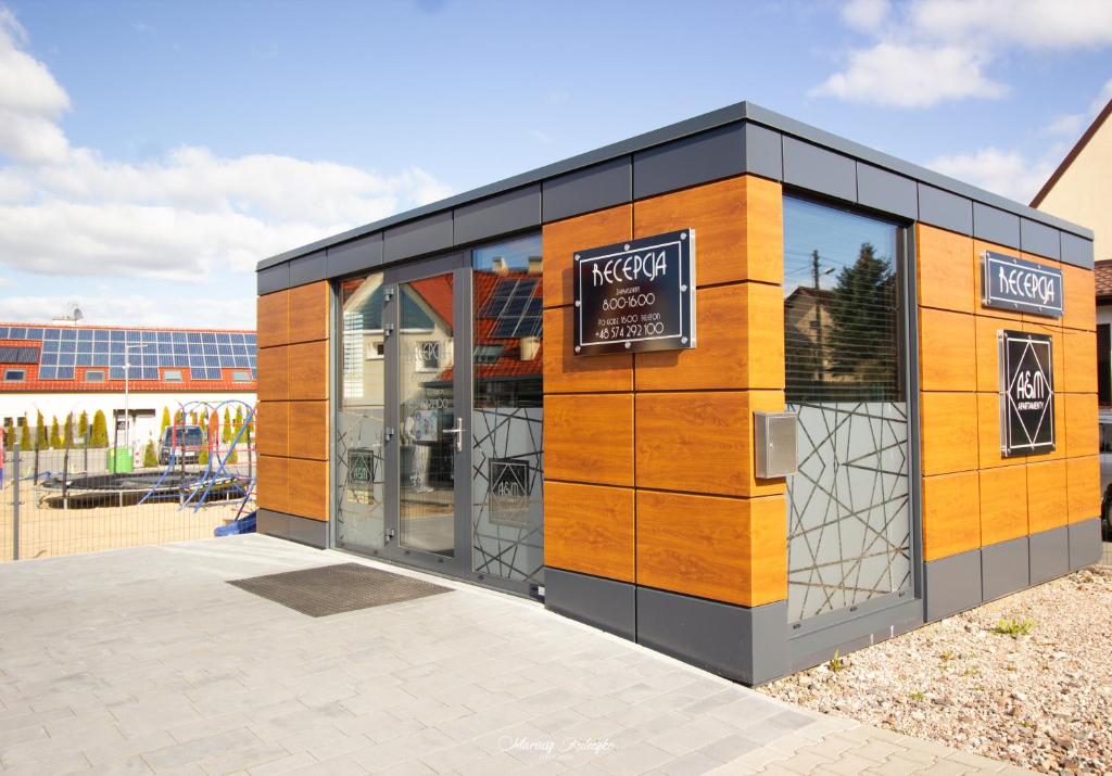 Small modern wooden-panel reception building with glass doors, playground and solar panels visible behind