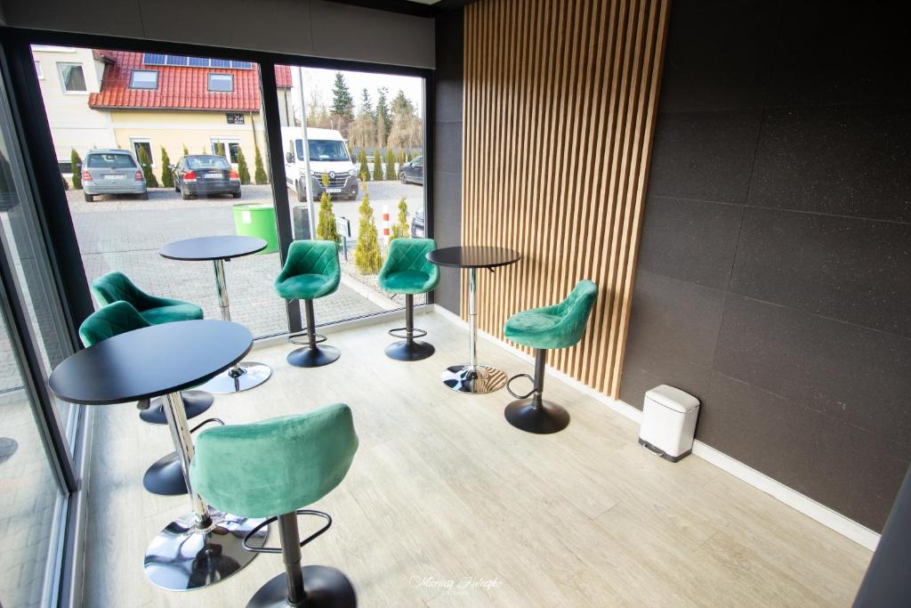 Modern lounge with green velvet bar stools, round black tables and floor-to-ceiling windows.