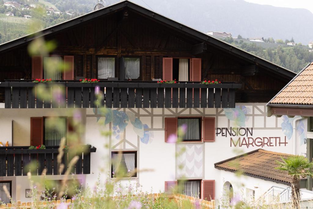 a building with a balcony with flowers on it at Pension Margreth in Rifiano