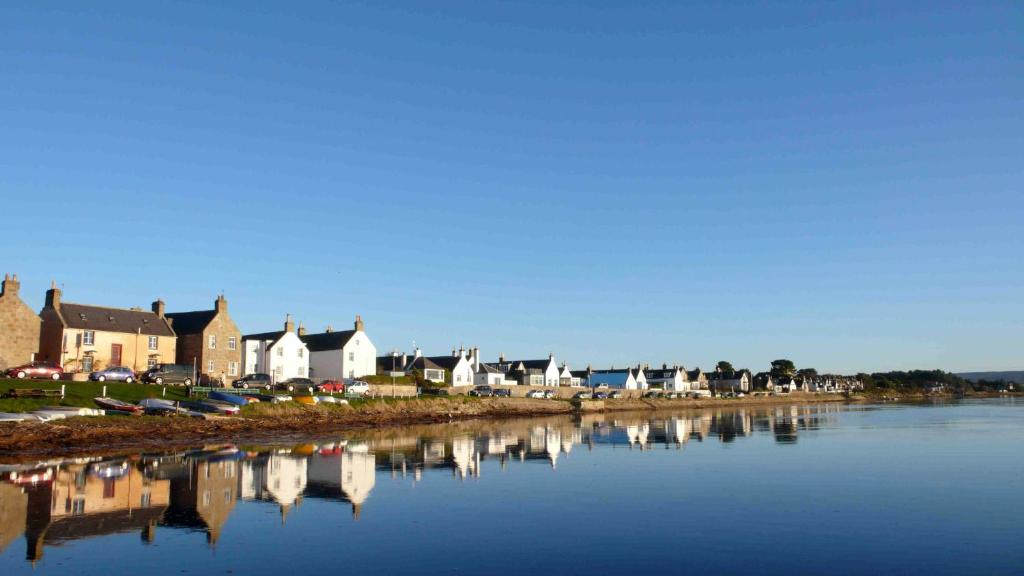a row of houses next to a body of water at Driftwood Cottage, Findhorn Village in Forres