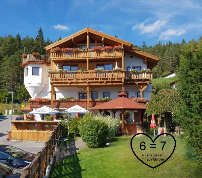 ein großes Holzgebäude mit einem Balkon und einem Herzen in der Unterkunft Krösbacher Hof in Seefeld in Tirol