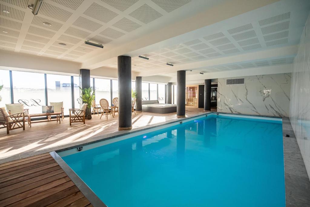 a large swimming pool in a building with a patio at Le Barracuda & Spa, Centre Port, pieds dans l'eau, vue mer in Brest
