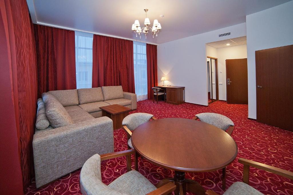 ein Wohnzimmer mit einem Sofa, einem Tisch und Stühlen in der Unterkunft Osnabruck Hotel in Twer