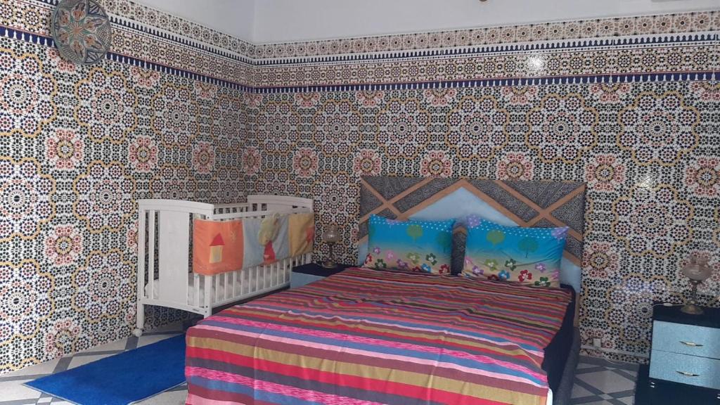 - une chambre avec un lit dans une pièce avec du papier peint dans l'établissement Mini Riad family Chez Adil Batha Fés, à Fès