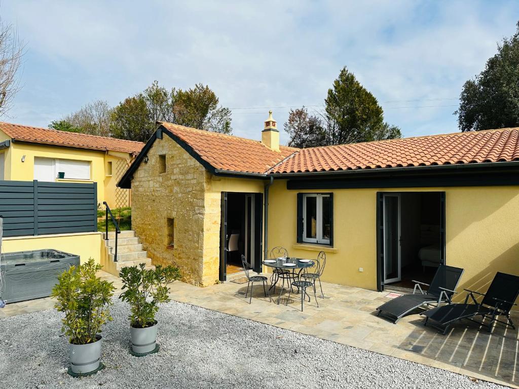 ein gelbes Haus mit einer Terrasse mit einem Tisch und Stühlen in der Unterkunft Les Gîtes De La Caneda in Sarlat-la-Canéda