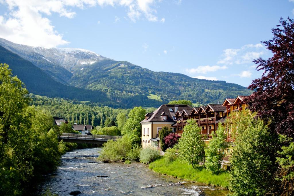 a river in a town with mountains in the background at Hotel Restaurant Platzer in Gmünd in Kärnten