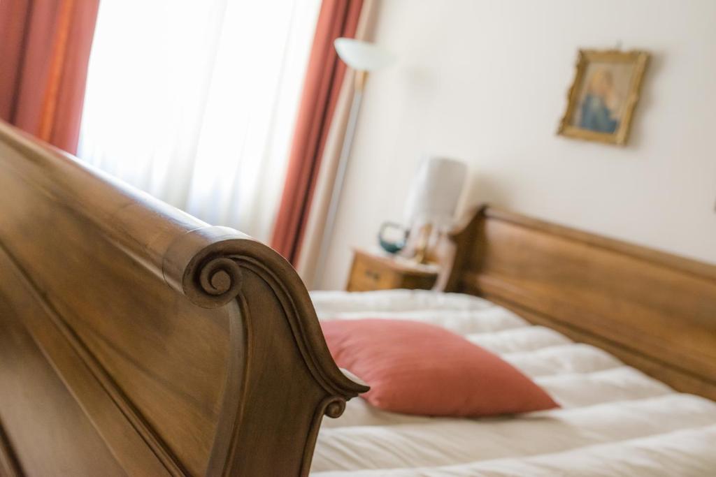 1 dormitorio con cama de madera y almohada rosa en B&B - Il Portichetto, en Asti