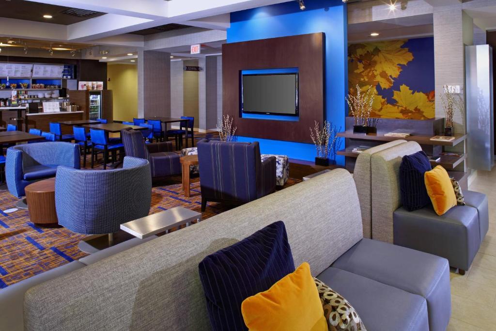 a lobby with couches and a restaurant with a bar at Courtyard Newark Granville in Newark