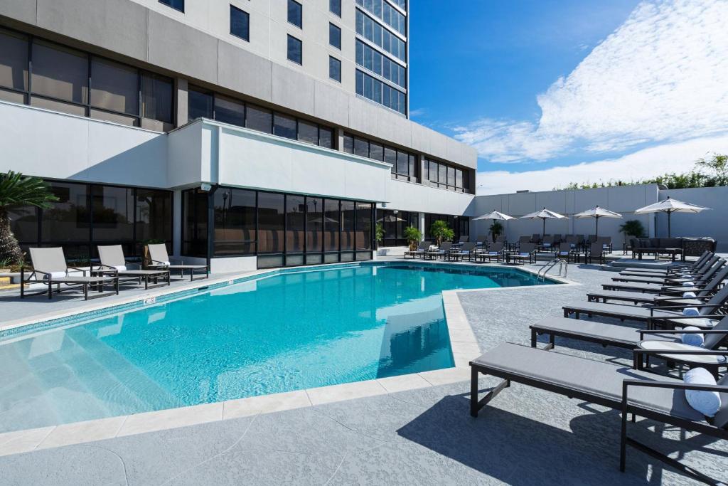 a swimming pool with lounge chairs and a building at Baton Rouge Marriott in Baton Rouge