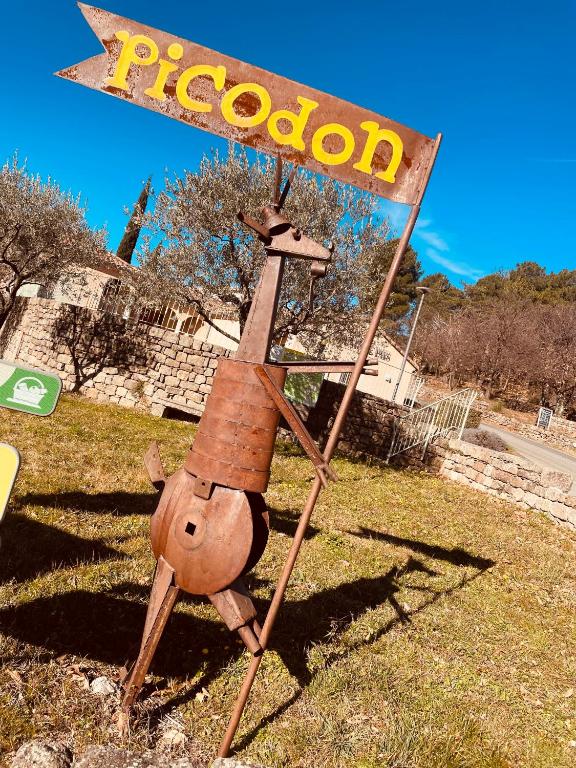 a wooden person with a sign in the grass at Le Planzollais in Planzolles