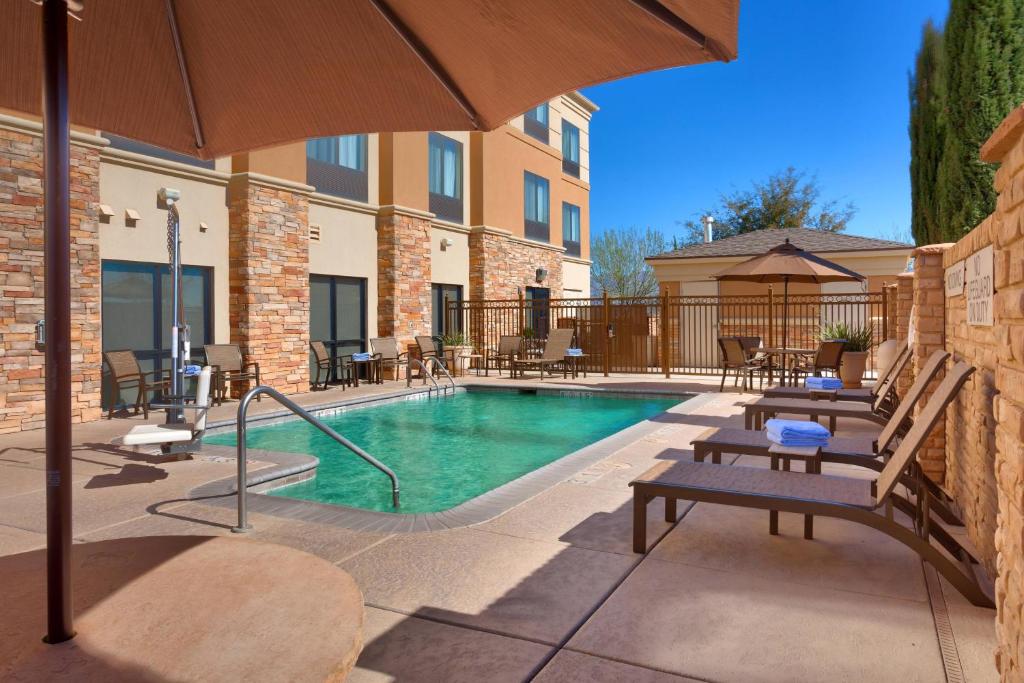 a swimming pool with benches and an umbrella at SpringHill Suites Thatcher in Thatcher