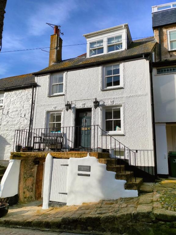 a white house with a staircase in front of it at Anchorage Guest House, St Ives in St Ives