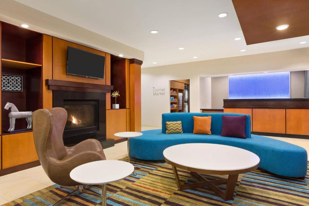 sala de estar con sofá azul y chimenea en Fairfield by Marriott Inn & Suites Houston North/Cypress Station, en Houston