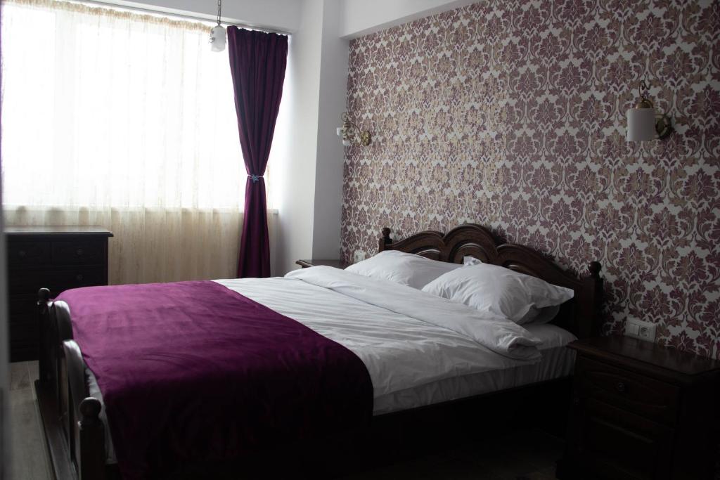 a bedroom with a large bed with purple and white sheets at Blue Joy Bukovina Aparthotel in Suceava