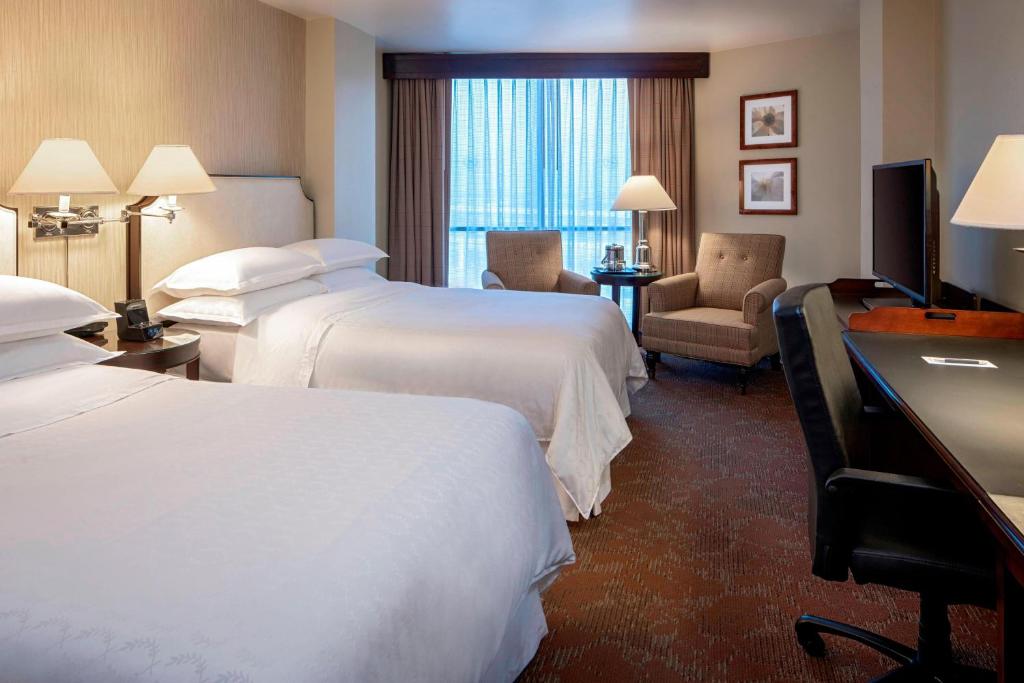 a hotel room with two beds and a television at Sheraton Houston Brookhollow in Houston
