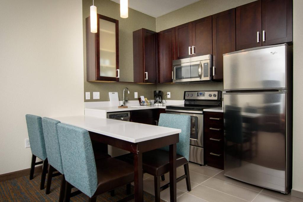 a kitchen with a table and a stainless steel refrigerator at Residence Inn by Marriott Cleveland Avon at The Emerald Event Center in Avon