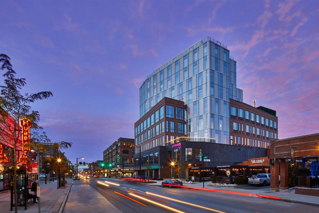 um edifício de vidro alto numa rua da cidade à noite em Moxy Columbus Short North em Columbus