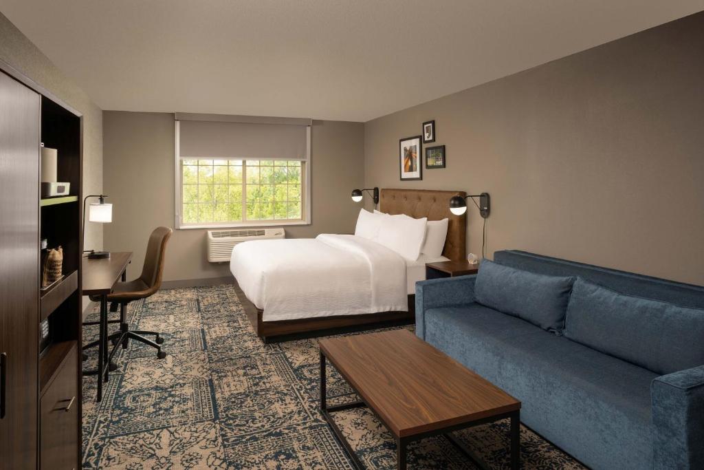 a hotel room with a bed and a couch at Four Points by Sheraton Chicago Schaumburg in Schaumburg