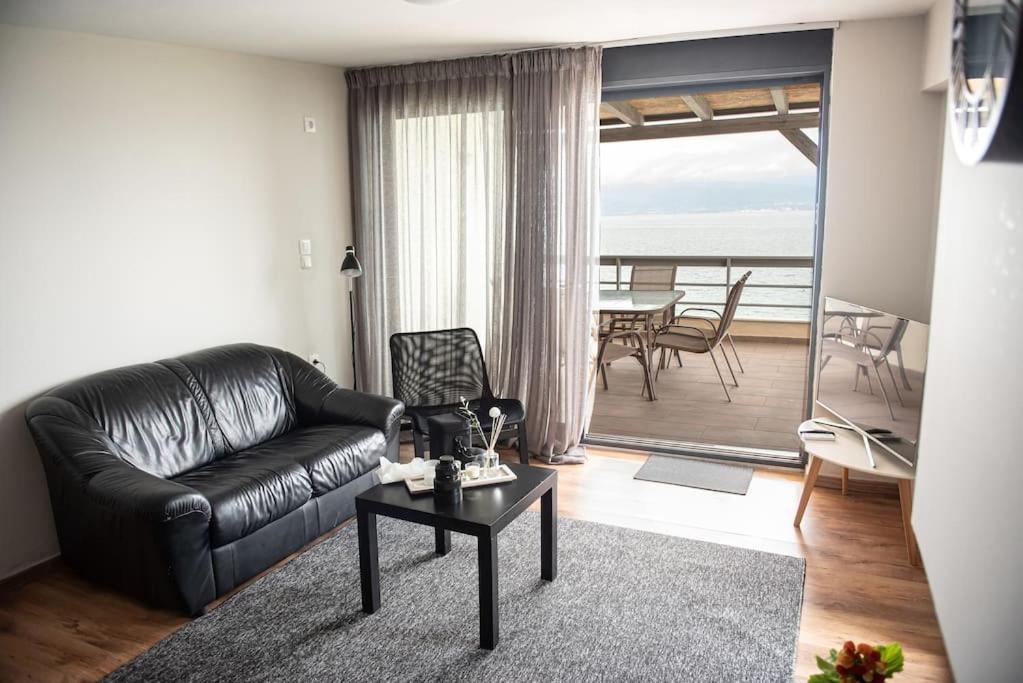 a living room with a black leather couch and a table at Seacoast apartments 3 ! in Kamena Vourla